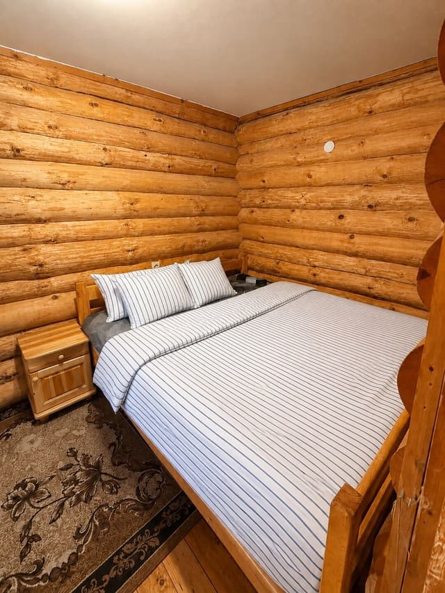 Two single beds joined with a mattress topper in a log-walled bedroom